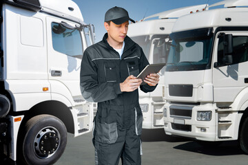 Fleet manager with digital tablet on a background of trucks