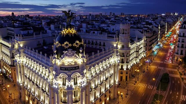 A breathtaking 4K ultra-HD aerial stock video capturing the stunning Madrid city skyline at twilight, with the iconic Gran V&iacute;a street illuminated by the warm glow of streetlights and neon signs.