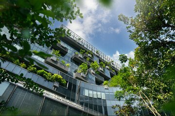 Eco-friendly building in modern city. Sustainable glass office building with trees for reducing...