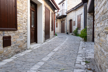 Obraz premium Narrow cobblestone street winding through traditional stone houses in cyprus