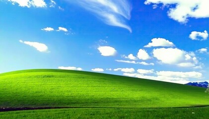 Fototapeta premium Soft focus of a blue sky over a rolling hill of green grass, grass, serene
