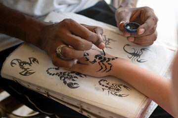 Handy master draws a henna drawing on a child's hand with a light-skinned