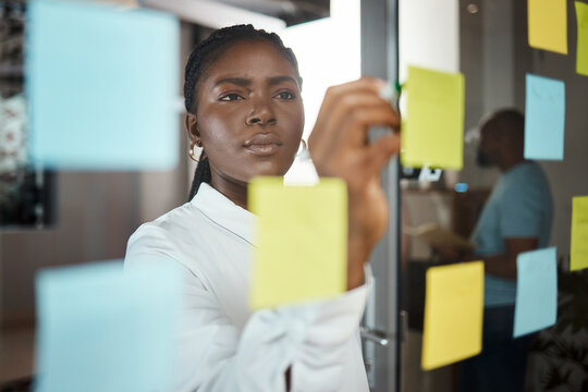 Office, black woman and writing with sticky note for brainstorming, planning session and writer. Glass, female employee and editor in creative agency for publication ideas, story solution or business