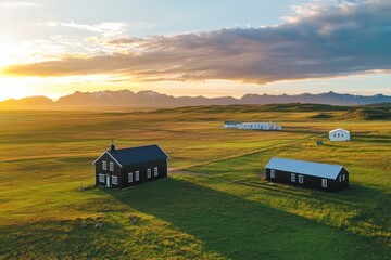 Fototapeta premium A black wooden church in Iceland with white windows and a blue roof, surrounded by green grass fields under the sunset sky.