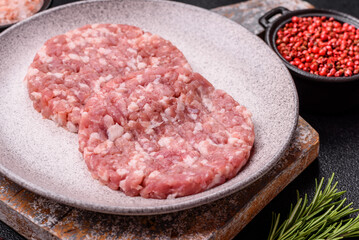 Fresh raw ground beef or pork burger patty with salt and spices