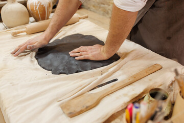Partial view of master pressing black clay in pottery studio
