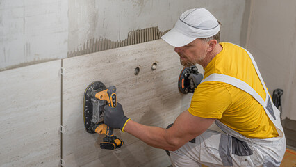 Tiling with large format tiles. A tiler placing a tile held by a tile suction cups.
