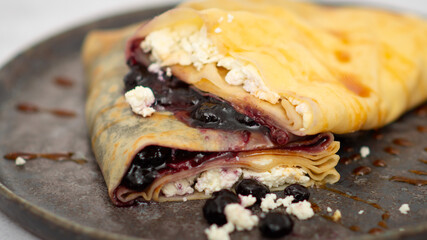 Delicious crepes with cottage cheese, jam, redcurrants and blueberries, closeup