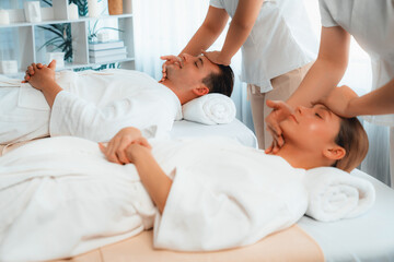 Fototapeta premium Caucasian couple enjoying relaxing anti-stress head massage and pampering facial beauty skin recreation leisure in dayspa modern light ambient at luxury resort or hotel spa salon. Quiescent