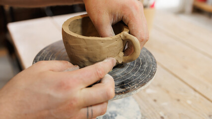 Close up view of potter making clay cup on wheel in workshop