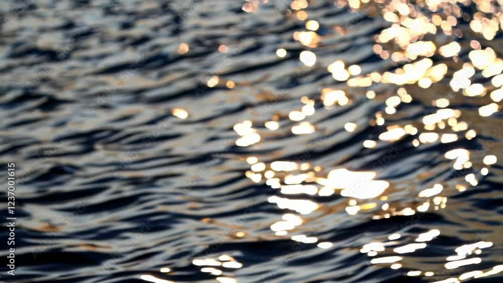 Aufkleber Sunlight reflecting off gentle ripples on the water’s surface, creating a shimmering golden bokeh effect. The abstract texture highlights the peaceful and calming movement of the waves.