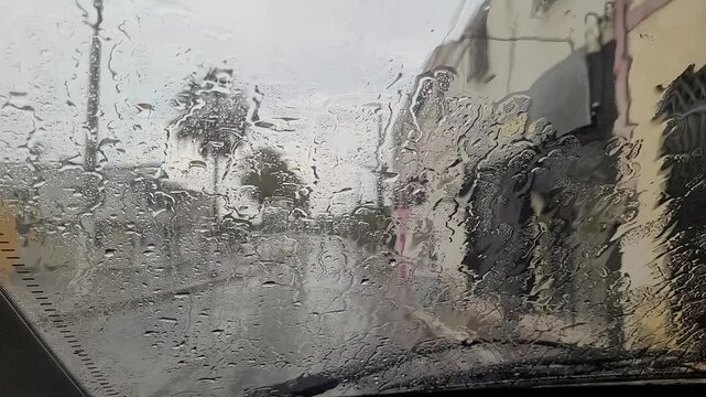 Chuva caindo sobre o para-brisa do carro em uma cidade
