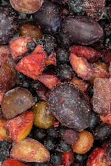 Frozen mixed fruits and berries as background, top view. Black plum, grapes, apples, mountain ash, grapes.