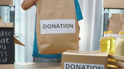 Close up hands volunteer proudly presents a bag of donations to the camera. Engaging in meaningful charitable activities at a donation center. Donation volunteers, charity work, food assistance
