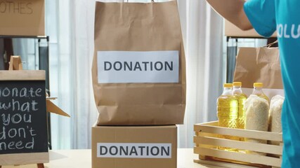 Close up hands volunteer proudly presents a bag of food donations to the camera. Engaging in meaningful charitable activities at a donation center. Donation volunteers, charity work, food assistance