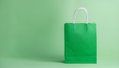 Green paper shopping bag on pastel green background. Mock-up.
