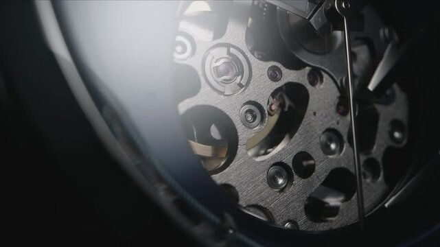 Men&rsquo;s Fancy Skeleton Watch Wide Angle Close-up. Second Arrow Running Across the Open Mechanism While Watch is Slowly Rotating. Shiny Metal Parts and Golden Moving Gears