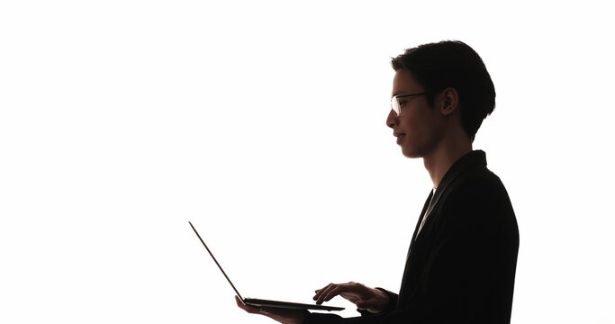 Working silhouette. Remote job. Digital marketing. Dark profile backlit outline of confident smart business man using laptop isolated on white empty space background.