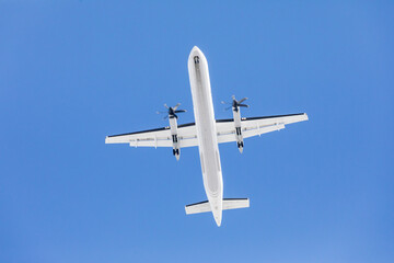 A turboprop is seen overhead on its final approach to an airport.