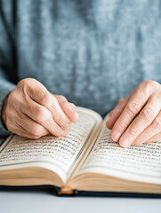 Fototapeta premium Elderly hands reading religious text with focus on arabic script and spiritual reflection.