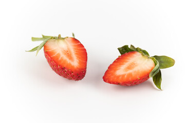 on white photo background there are cut two halves of one ripe strawberry, healthy vitamins, seasonal summer fruit, vitamin C green strawberry tail like a crown