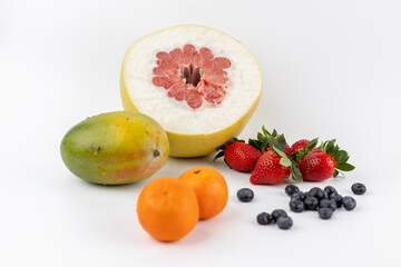 closeup composition of tangerine and pamela fruits lies on a white background and strawberries blueberries and mangoes environmentally friendly product vitamin