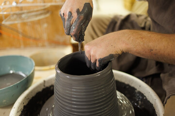 Cropped shot of artisan molding clay vase on wheel in studio