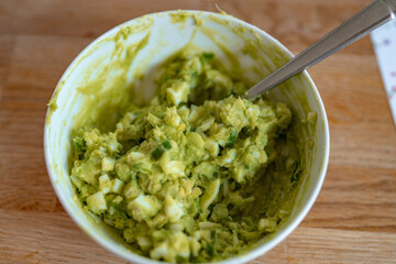 Perfectly blended guacamole with finely chopped ingredients in a white bowl