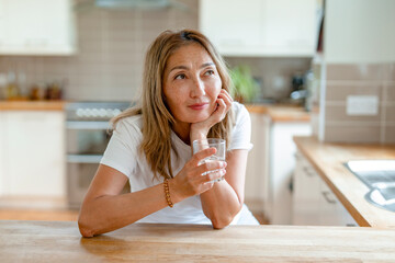 Woman enjoying a refreshing drink while contemplating in a modern kitchen setting