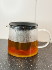 Pouring Hot Water into a Glass Teapot for Brewing Tea. High quality photo Boiling water is poured from a stainless steel kettle into a glass teapot with a metal infuser. The tea leaves begin to steep