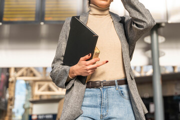 Stylish businesswoman holds a notebook while standing in a modern urban setting