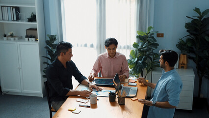 Top view of team working together to brainstorm idea while project manager talking to phone at meeting room. Male leader calling investor and present plan while team discussing strategy. Convocation.