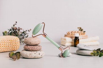 Jade facial massager, spa items and pebbles on table