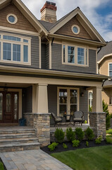 Luxury House Exterior: Modern Architecture and Landscaping Design. Stunning Facade with Stone Details, Spacious Porch, and Well-Maintained Garden