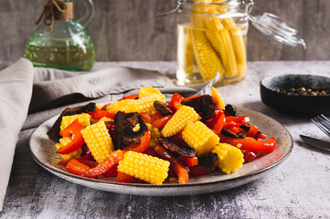 Appetizing salad of canned corn, fried mushrooms and peppers on a plate on the table