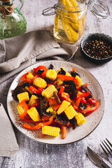 Vegetarian salad with corn cobs, mushrooms and peppers on a plate on the table vertical view