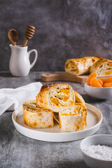 Sweet roll of cottage cheese with tangerine wrapped in lavash on a plate on the table vertical view