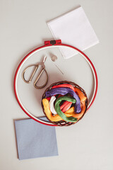 Basket with colored floss and canvas for embroidery on a gray top and vertical view