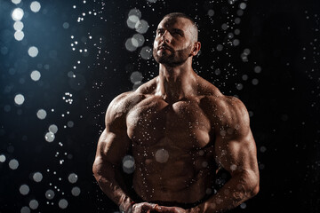 Muscular man under the rain in studio. Sexy male in water drops, abs