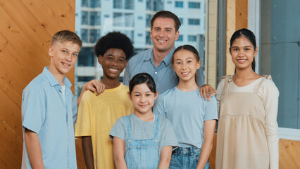 Happy teacher and diverse student standing while smilling to camera. Professional smart instructor with highschool children with mixed races in casual outfit pose at camera with cheerful. Edification.