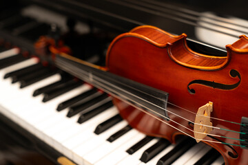 Fototapeta premium Violin on top of piano keyboard background