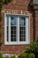 Fototapeta premium Elegant White Window on Red Brick House Exterior. Classic Architecture, Home Design, Real Estate