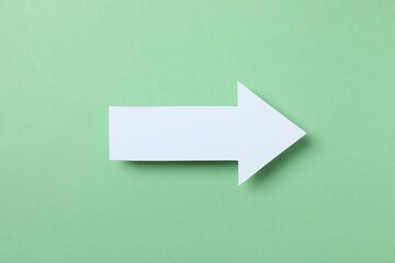 Paper arrow on color background, top view