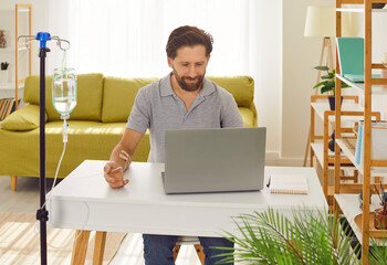 Young man sitting and working on a laptop at the desk of his workplace at home or in office while...