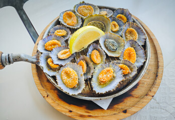 Grilled limpets served on a cast iron with a lemon slices in a restaurant in Azores island. Typical...