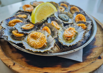 Grilled limpets served on a cast iron with a lemon slices in a restaurant in Azores island. Typical...