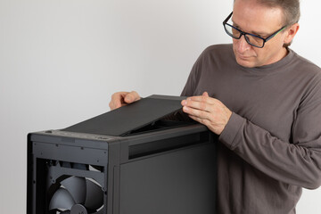 Man installing  top panel with dust filter to  PC case, empty big tower, chassis. Under top panel is place for 420 mm radiator for AIO cooling