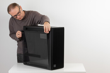 Man removing  tempered-glass left panel from  PC case, empty big tower, chassis.