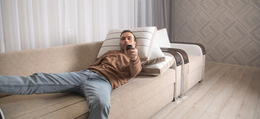 Caucasian man showing Tv controller at home.