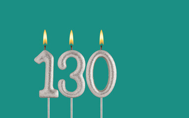 Birthday candle number 130 - Card on a green background.
